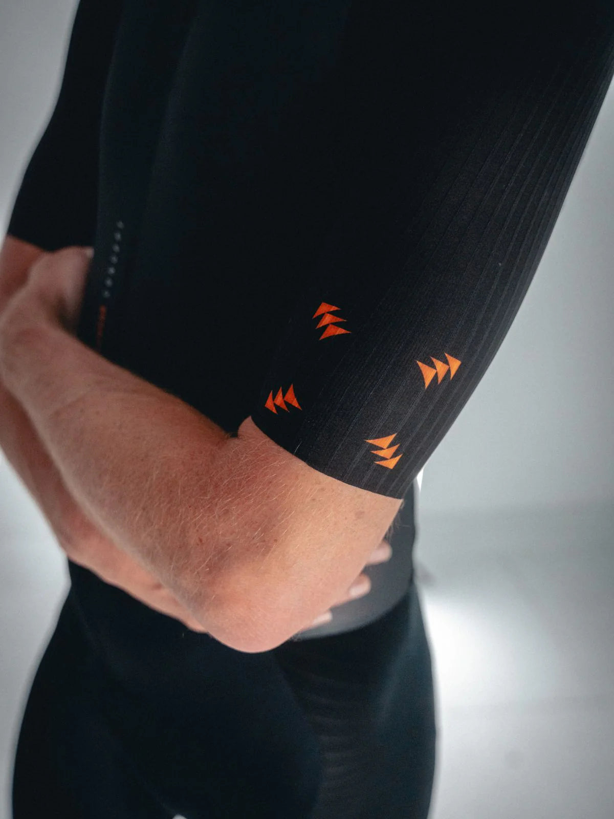 Close-up of a person wearing black athletic leggings with orange accents on a gray background