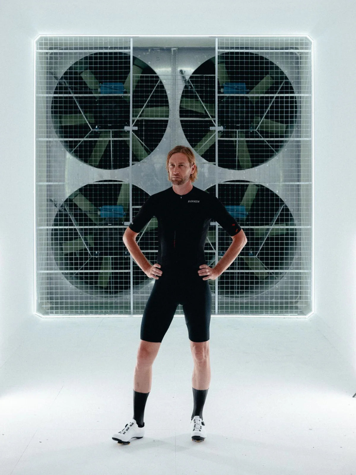 Person wearing a black athletic outfit standing in front of a large grid with circular patterns.