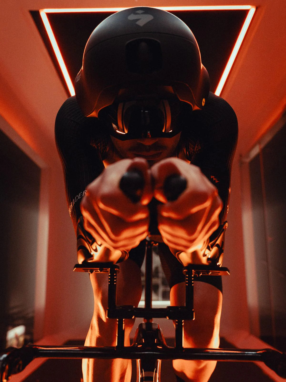 Person on a stationary bike with a helmet in a dimly lit room with red lighting