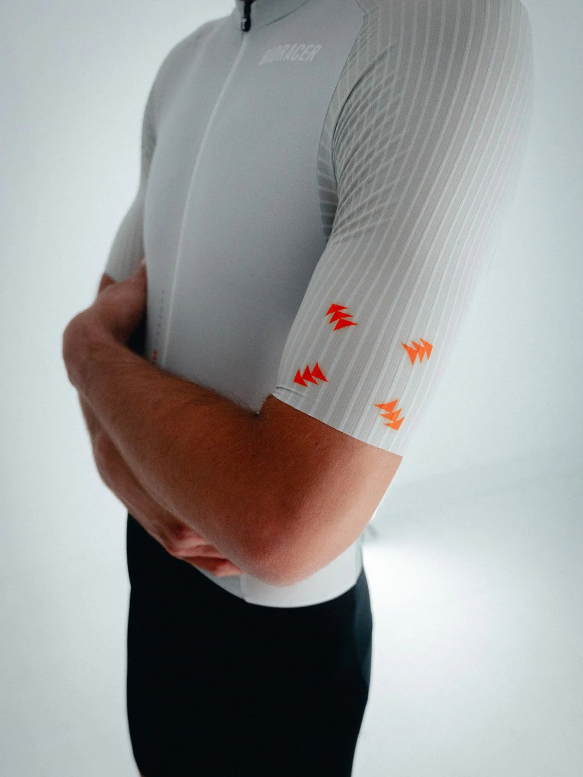 Person wearing a white cycling jersey with orange accents on a light gray background