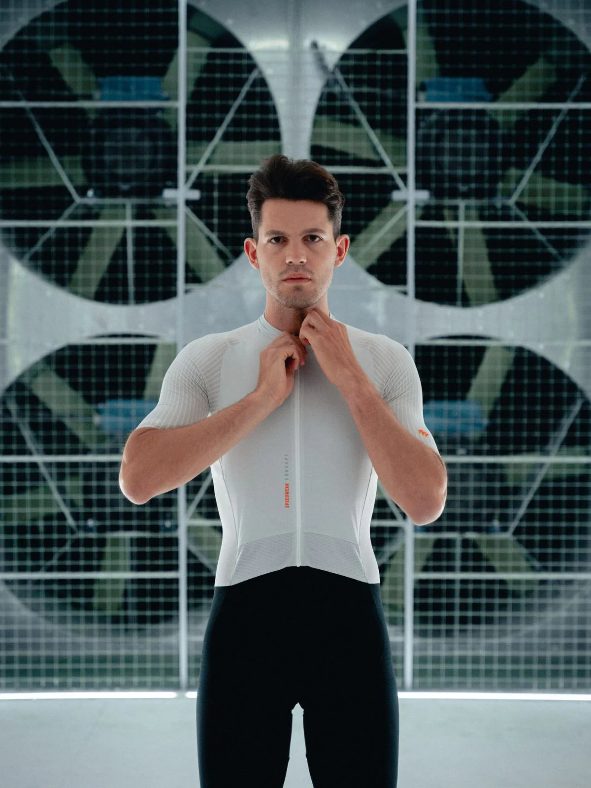 Man wearing a white cycling jersey in front of a geometric patterned wall.